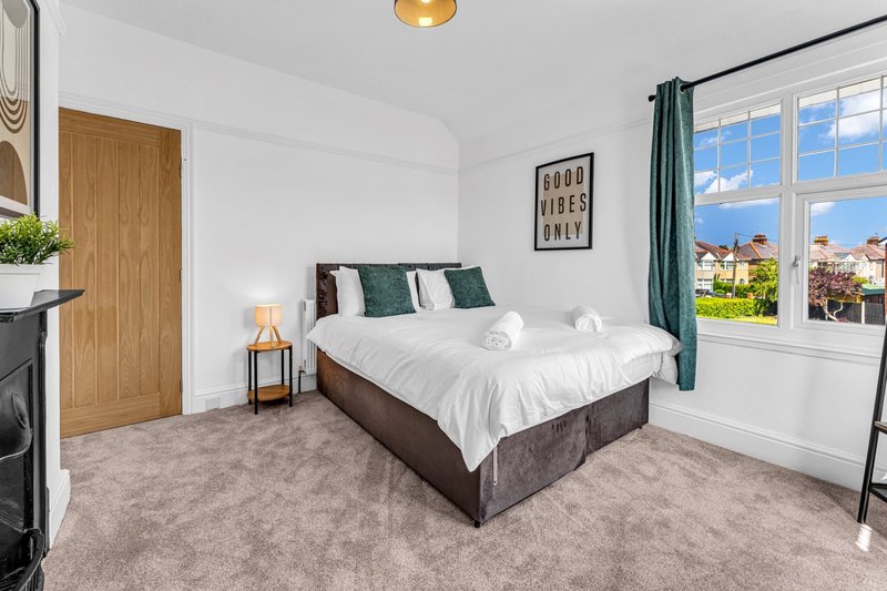 Bright bedroom with double bed, wooden door, large windows and countryside view