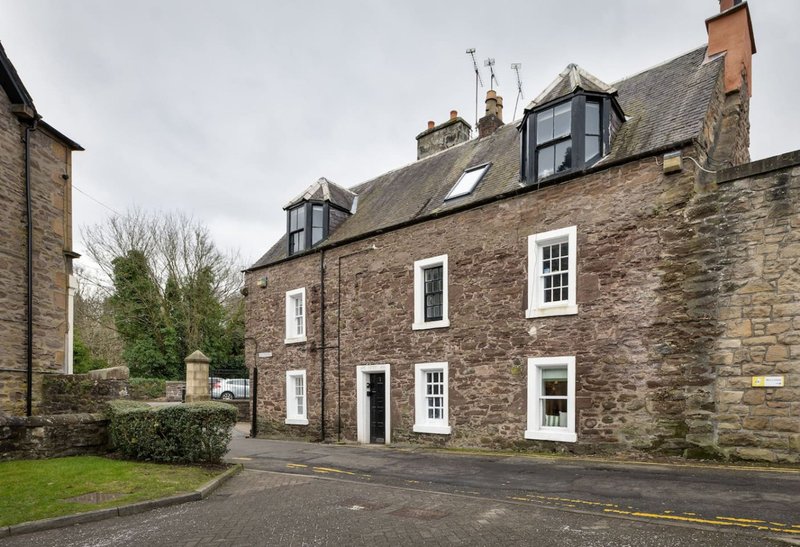Stone-built residential property with multiple windows, mansard roof, and front driveway