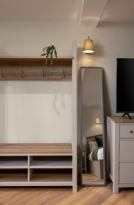 Modern entryway with wooden coat rack, storage bench, mirror and pendant lighting