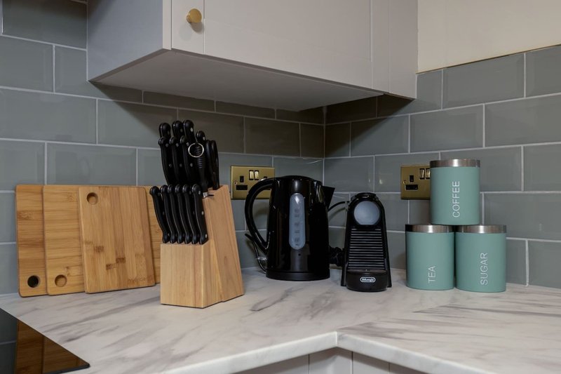 Modern kitchen countertop with marble surface, knife block, kettle, and branded storage canisters