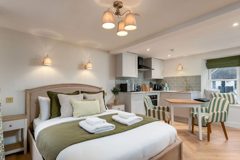 Modern studio bedroom with double bed, kitchenette, dining area and pendant lighting