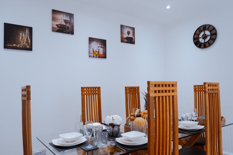 Dining room with wooden chairs, set table, framed wall art and decorative clock