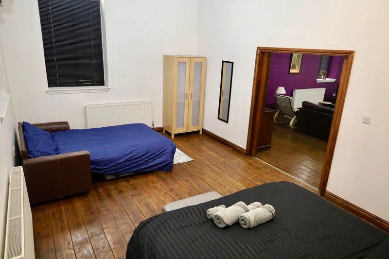 Shared bedroom with two beds, wooden floor, radiator and wardrobe