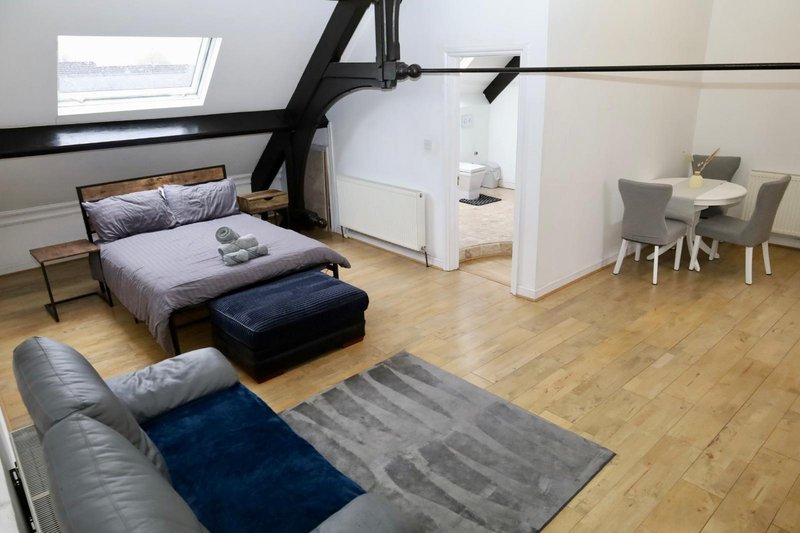 Loft bedroom with double bed, skylight, wooden floor, sofa and dining area