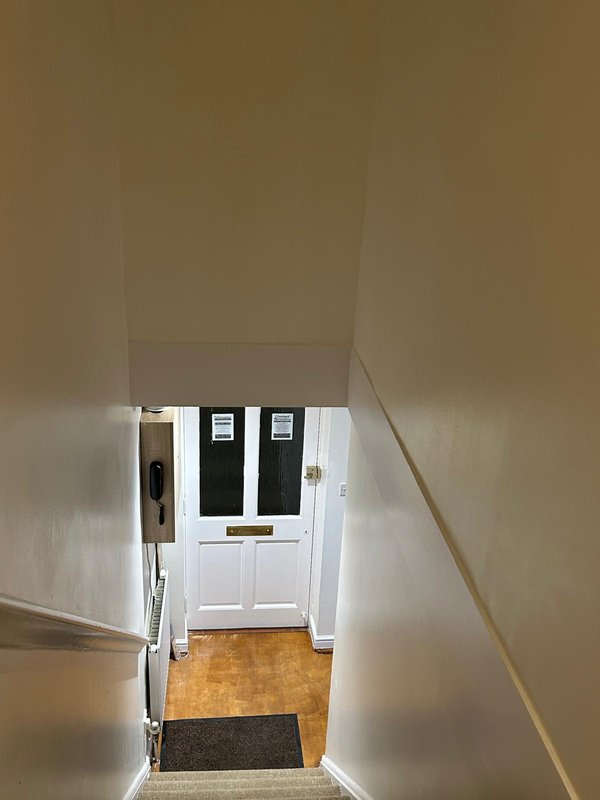 Stairwell looking down to white front door with black panels and entrance hall