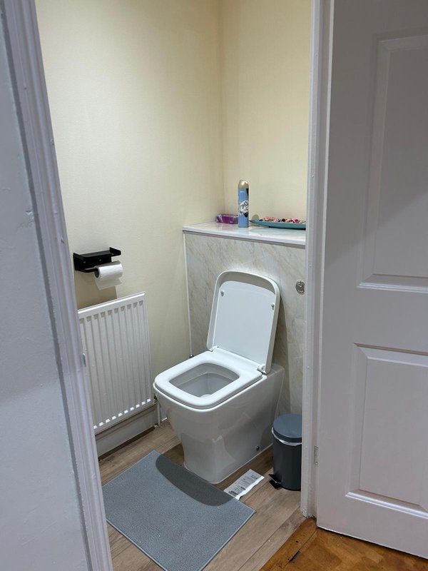 Small bathroom with toilet, radiator, sink cabinet and cream walls