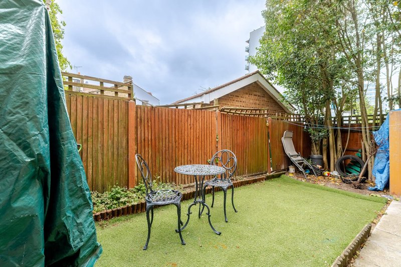 Enclosed garden with lawn, metal furniture, corrugated fence and green garden screening