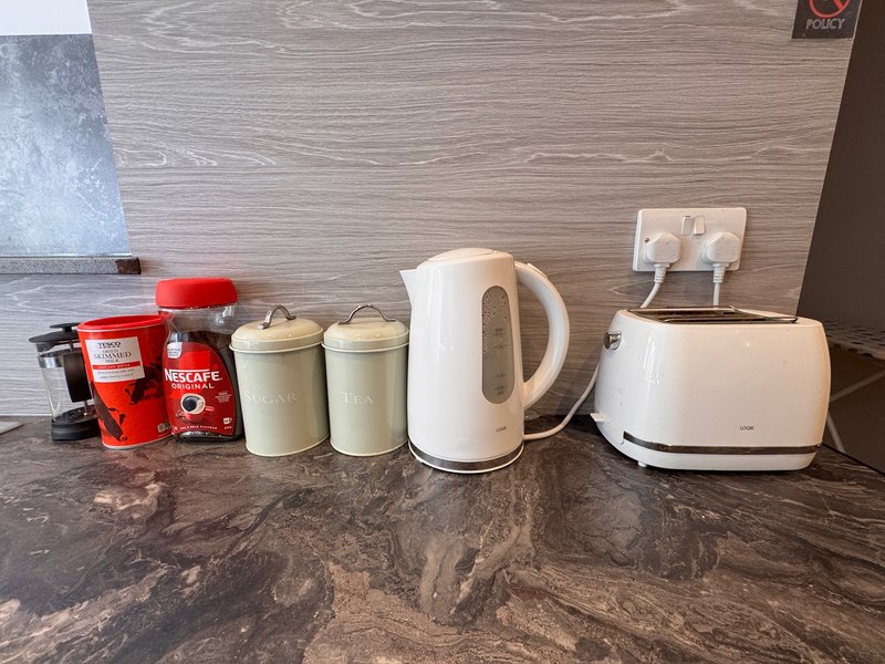 Kitchen counter with white kettle, toaster, red coffee maker, and storage containers