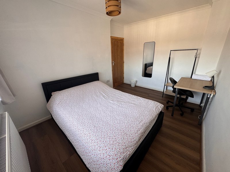 Bedroom with double bed, wooden floor, desk, and wall-mounted mirrors