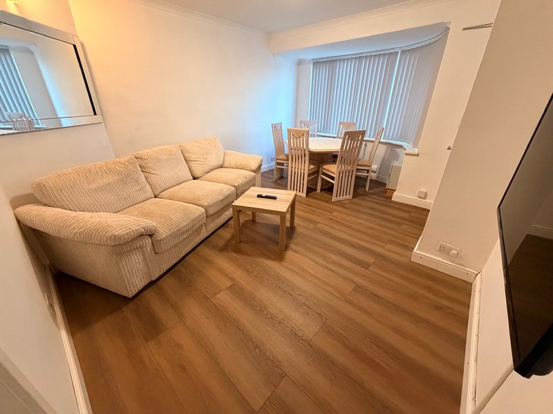 Living room with cream sofa, dining table, chairs, wooden floor and large windows