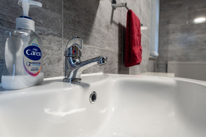 Modern bathroom sink with chrome tap, hand soap dispenser and red towel