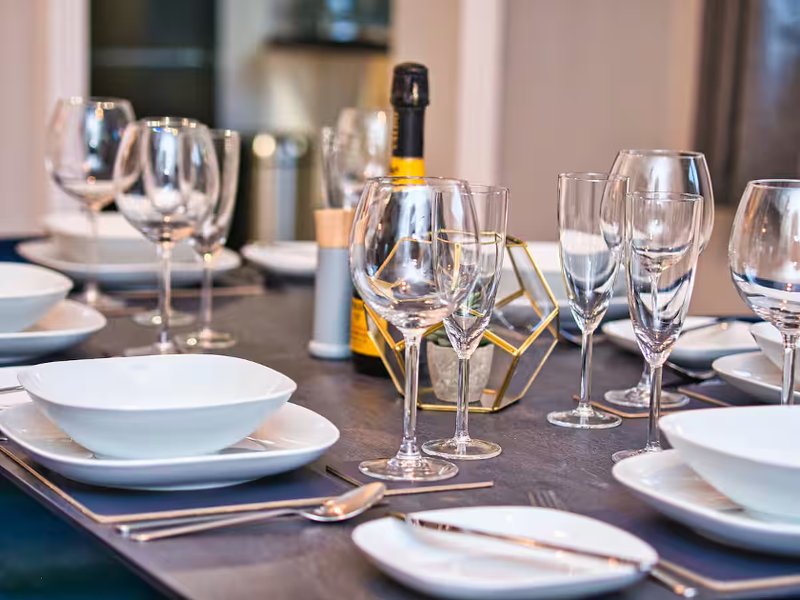 Formal dining table set with wine glasses, place settings, and bottle centerpiece