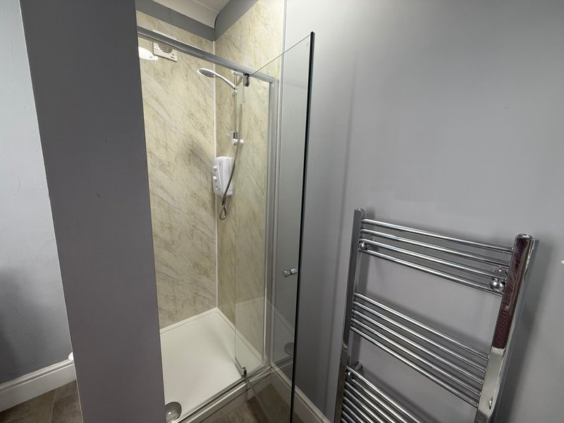 Modern bathroom with walk-in shower enclosure, tiled walls, and chrome heated towel rail