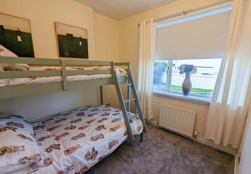 Bedroom with bunk beds, carpet, window with countryside view, and cream curtains