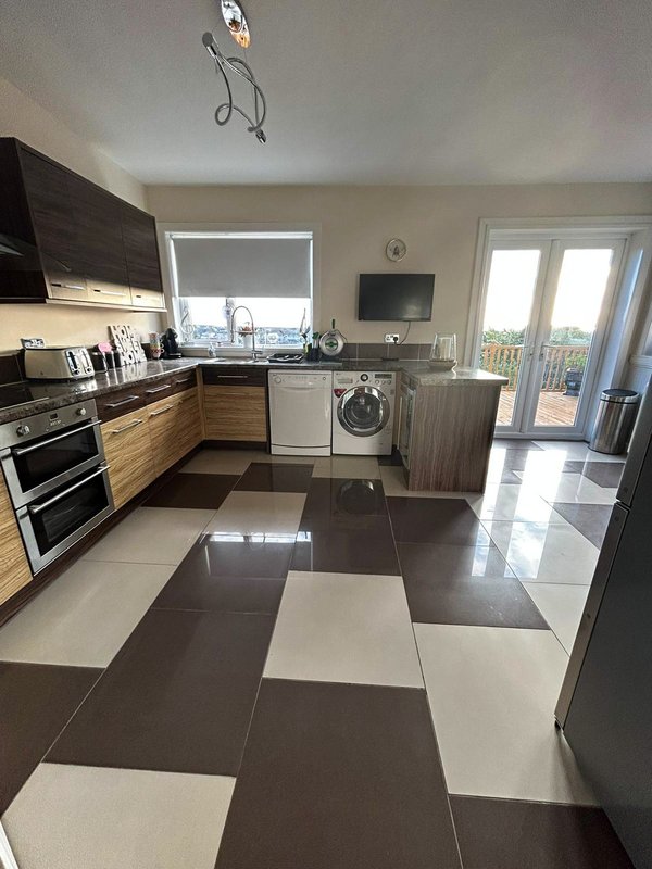 Modern kitchen with wooden cabinets, stainless steel appliances, checkered tile floor and glass patio doors