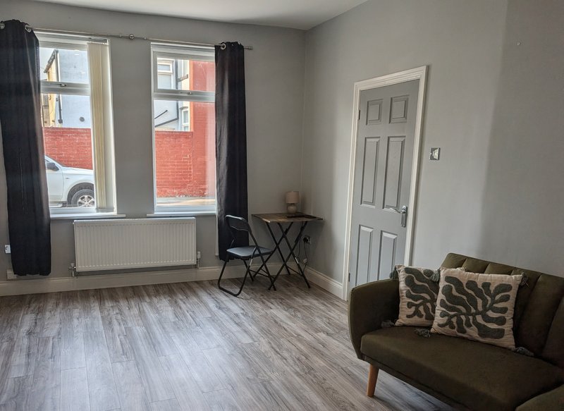 Bright living room with brown sofa, wooden floor, large windows and white door