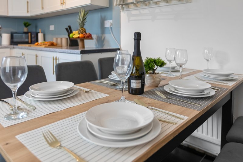 Modern dining table set for multiple guests with wine bottle, glasses and place settings