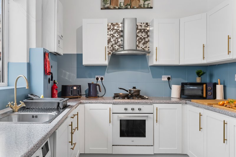 Modern kitchen with white cabinets, blue backsplash, stainless steel appliances and countertops