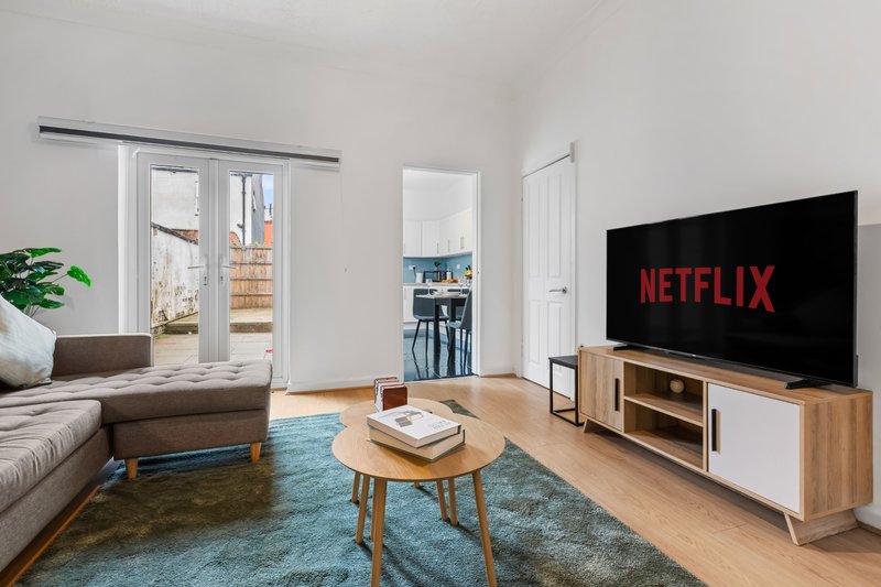 Modern living room with sofa, wooden coffee table, TV on stand, and access to balcony
