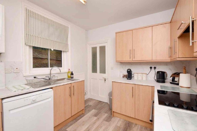 Modern kitchen with light wood cabinets, white countertops, and integrated appliances