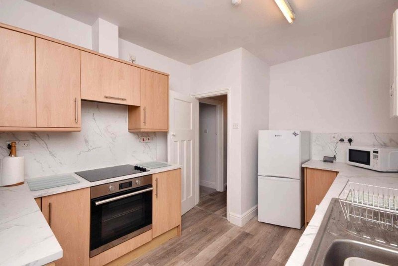 Modern kitchen with wooden cabinets, marble backsplash, integrated oven and white appliances