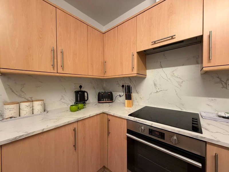 Modern kitchen with wooden cabinets, marble countertop, stainless steel electric oven and appliances