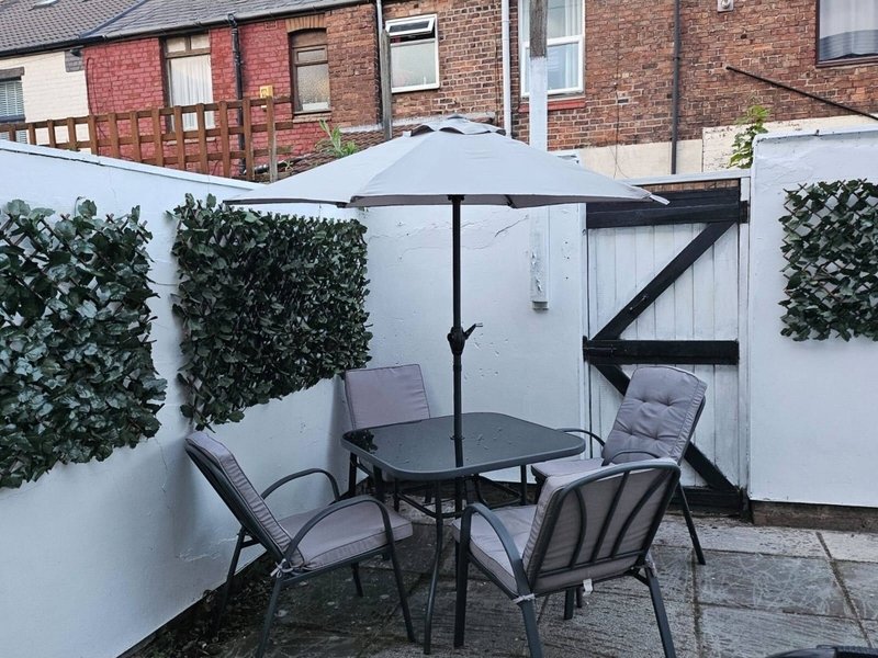 Outdoor patio with dining table, chairs, umbrella and artificial ivy screening