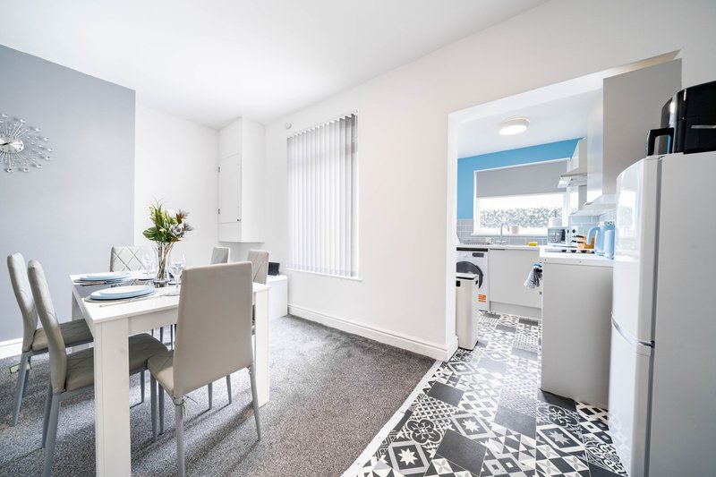 Open-plan kitchen and dining area with white cabinetry, dining table, and vertical blinds