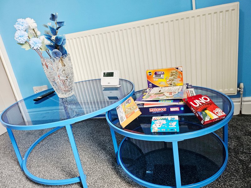 Blue round tables with board games, flowers in vase, radiator and white wall behind