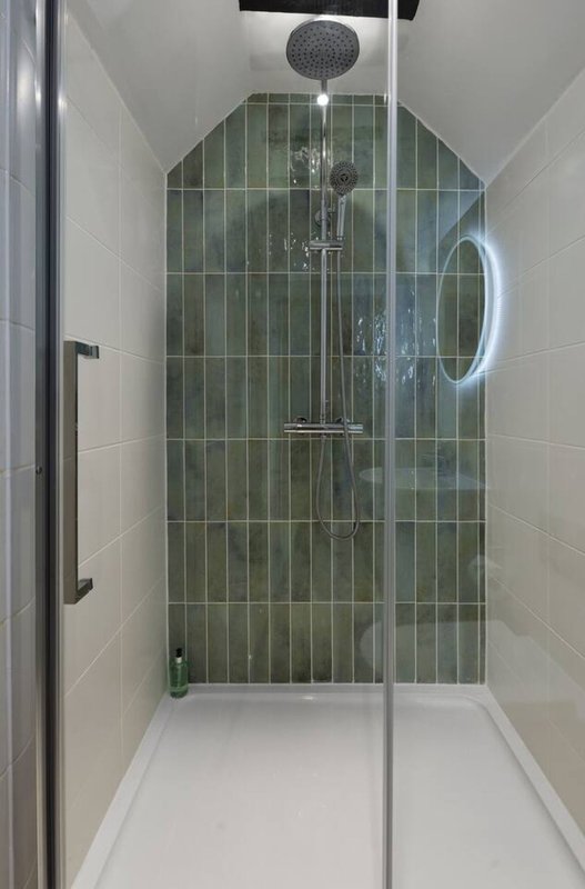 Modern bathroom shower enclosure with green tile walls and rainfall showerhead