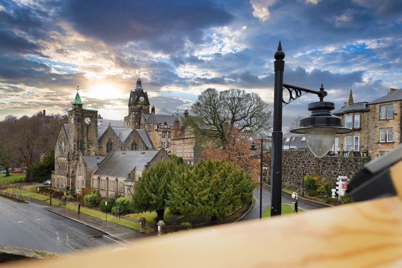 Elevated view of stone church with spires surrounded by trees and residential buildings