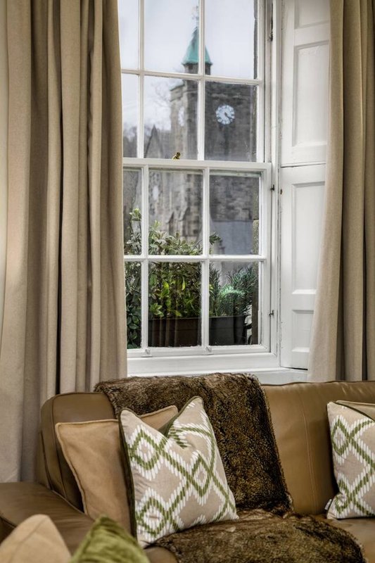 Living room with cream sofa, patterned cushions, and window view of church tower