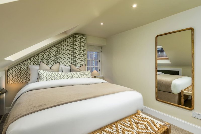 Modern bedroom with double bed, patterned headboard, mirror and recessed ceiling lights