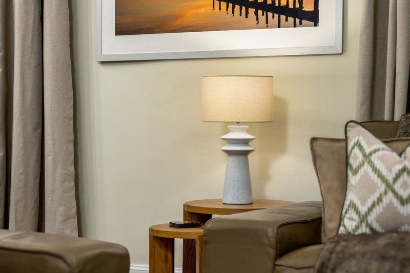 Living room with upholstered armchair, wooden side table, table lamp and framed wall art