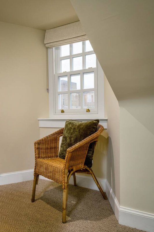 Bright corner with wicker chair, green cushion, and large multi-pane window