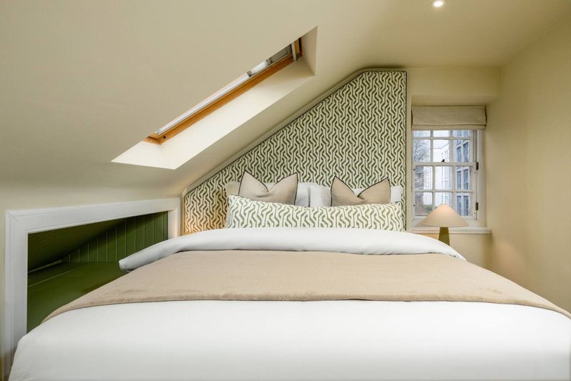 Modern bedroom with double bed, patterned headboard, skylight and green accent wall