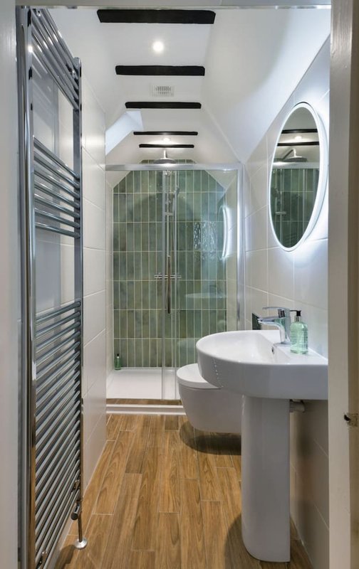 Modern bathroom with walk-in shower, pedestal sink, heated towel rail and wooden flooring
