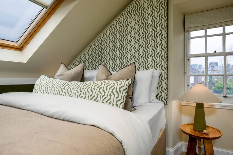 Attic bedroom with double bed, patterned headboard, skylight and city views