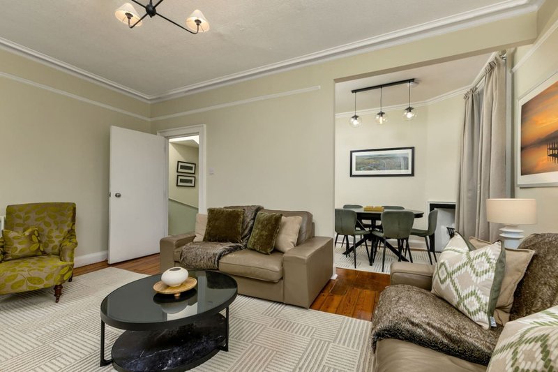 Open-plan living and dining area with neutral furnishings, black coffee table, and pendant lighting