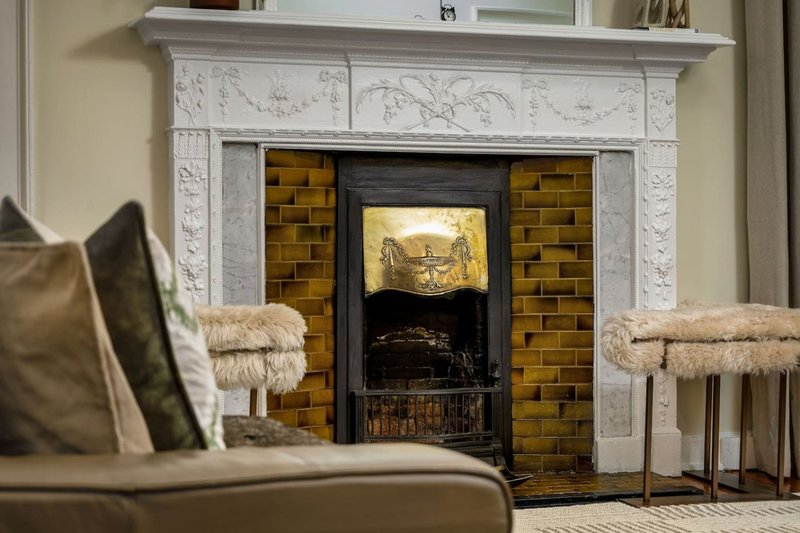 Living room with fireplace, decorative mantelpiece, sofa with cushions and throws