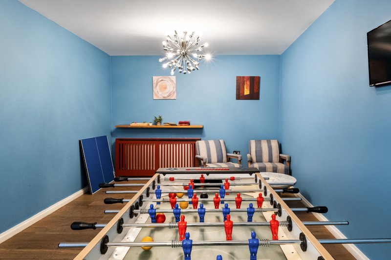 Blue recreation room with foosball table, radiator, chandelier, and wall art