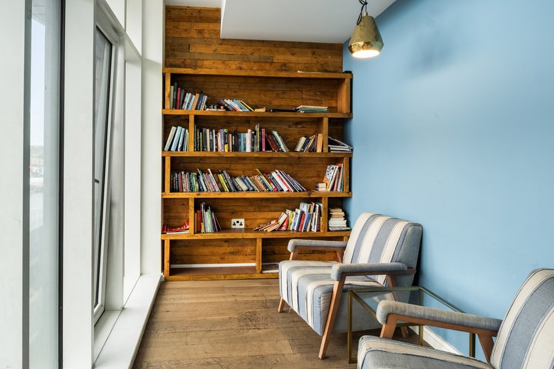 Reading nook with wooden built-in bookshelf, two striped armchairs, and pendant lamp
