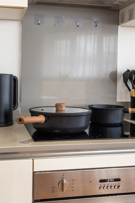 Kitchen stovetop with black cookware, wooden handles, and stainless steel appliance