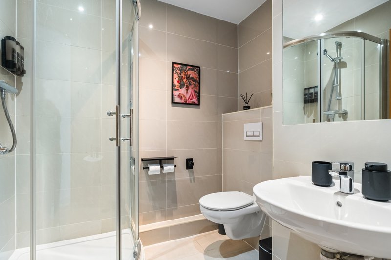 Modern bathroom with double sink, toilet, walk-in shower and mirror