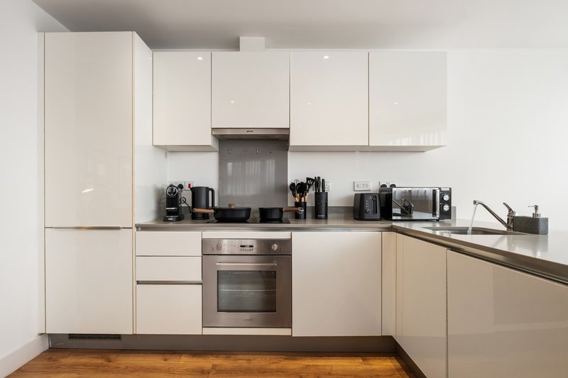 Modern kitchen with white cabinetry, stainless steel appliances, and wooden flooring