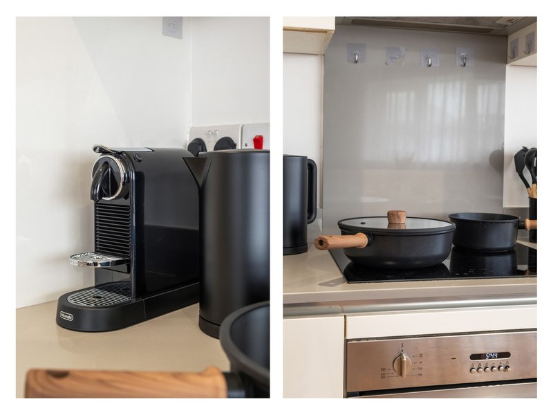 Kitchen counter with coffee machine, water kettle, and cookware on stovetop