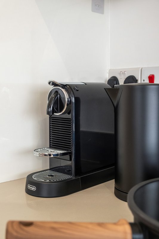 Kitchen counter with black espresso machine, milk frother, and coffee accessories