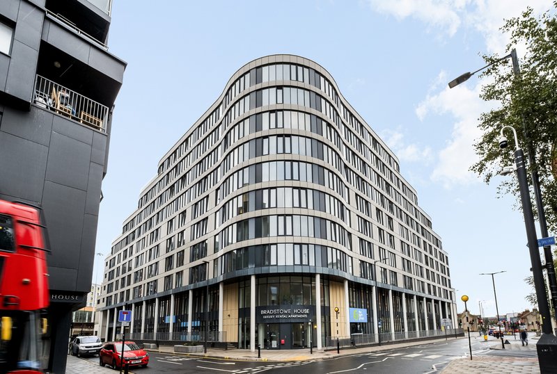 Modern curved residential building with multiple floors, street-level retail, and urban surroundings