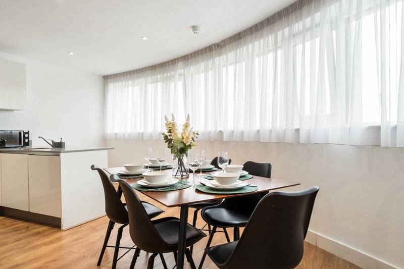 Modern dining area with black table, chairs, place settings and yellow flowers in vase