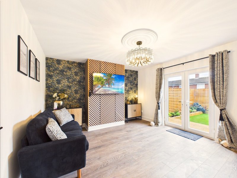 Spacious bedroom with dark feature wall, comfortable seating, ceiling light fixture and garden doors